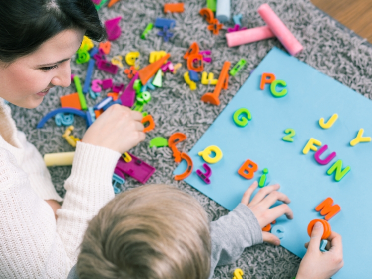 Pani bawiąca się literkami z małą dziewczynką